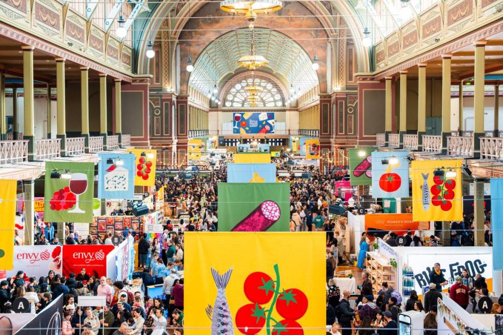 Crowds fill The Little Food Market in Melbourne, with colourful food stalls and banners throughout the venue