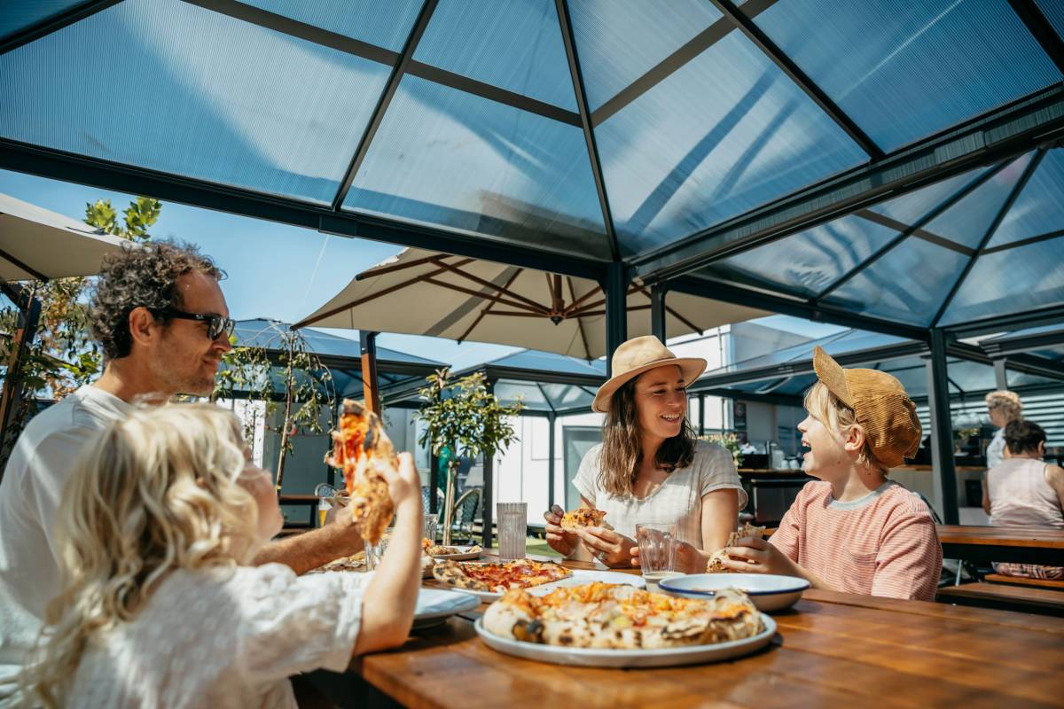 A family enjoying pizza together at an outdoor restaurant in Eden on the NSW South Coast