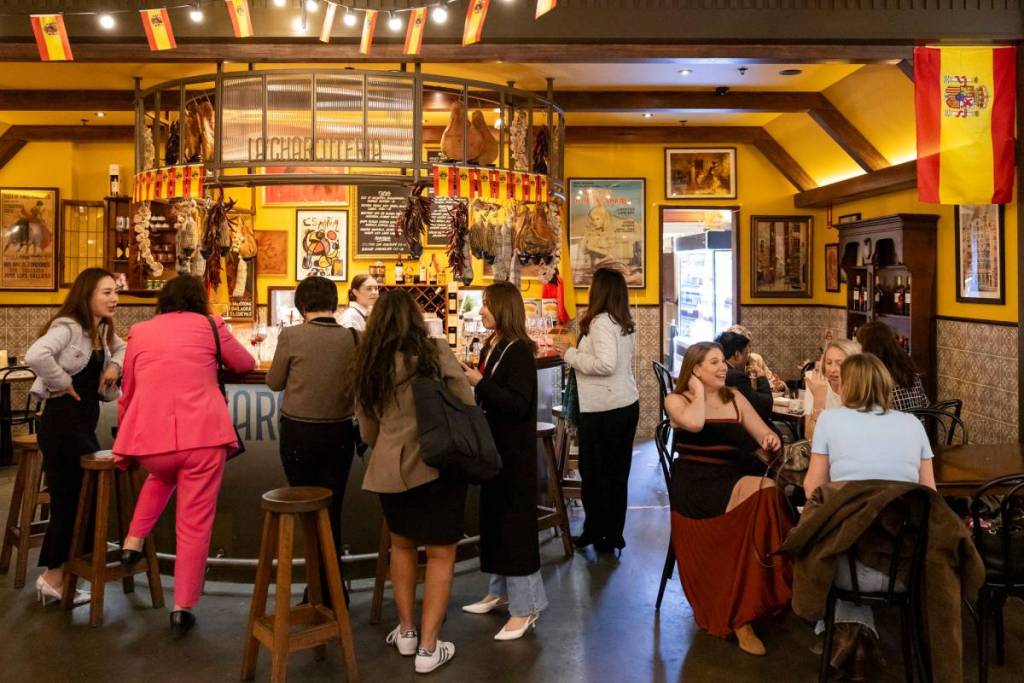 a group of people gather around the bar at La Charcuteria Hay Street