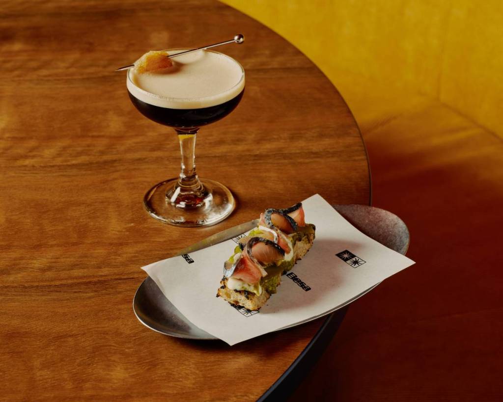 An espresso martini and a small dish on a wooden table