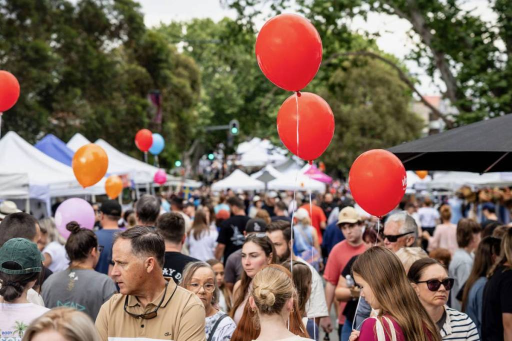 Crowds fill a Sydney street festival lined with market stalls and colourful balloons