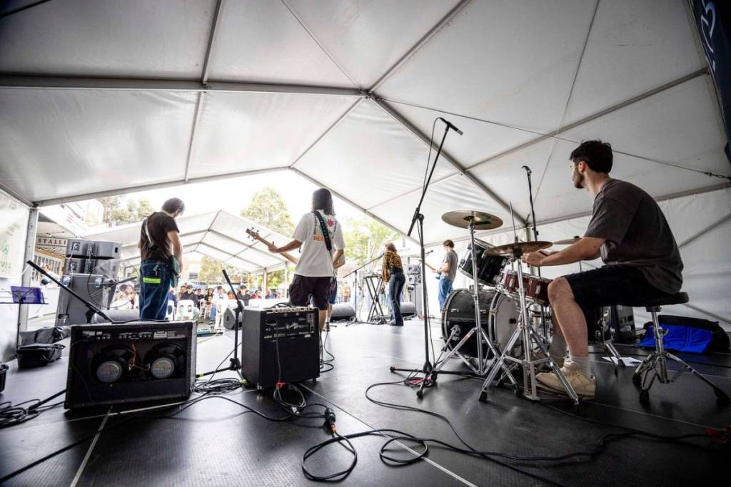 A live band performs on stage under a marquee at Engadine street festival