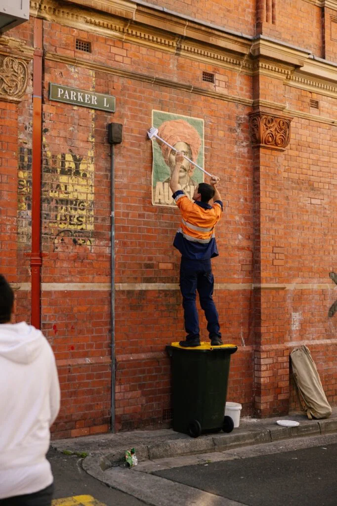 Peter Drew pasting Aussie posters in Sydney