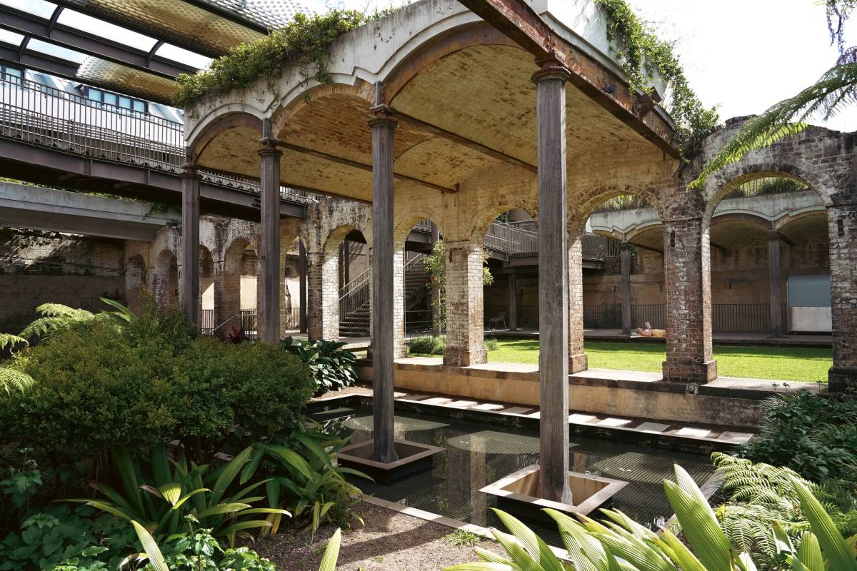 Preserved brick arches, timber columns and a reflective pond inside Paddington Reservoir Gardens