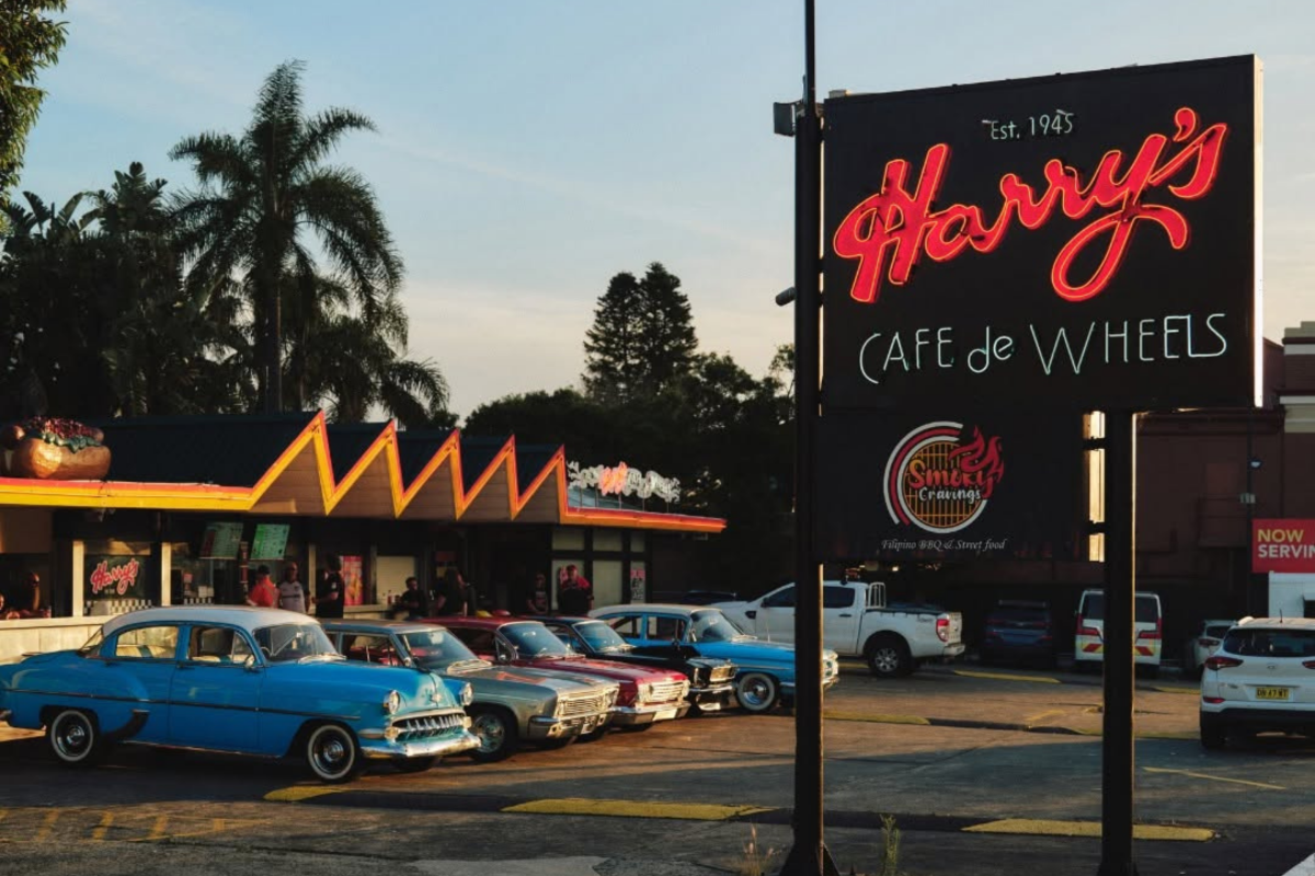 Harry's Café de Wheels signage overlooking a row of vintage cars parked outside a Sydney outlet