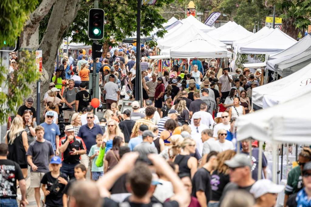 Large crowds fill Gymea Bay Road, with market stalls stretching along both sides of the street
