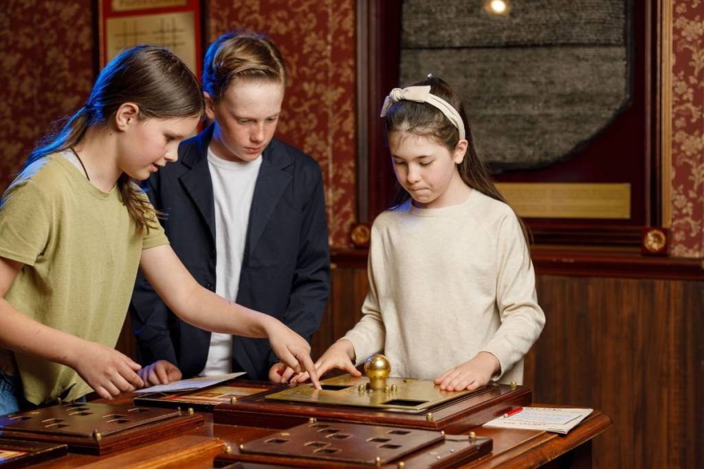 A young boy and two young girls solve puzzles on a table at Top Secret: License to Spy.