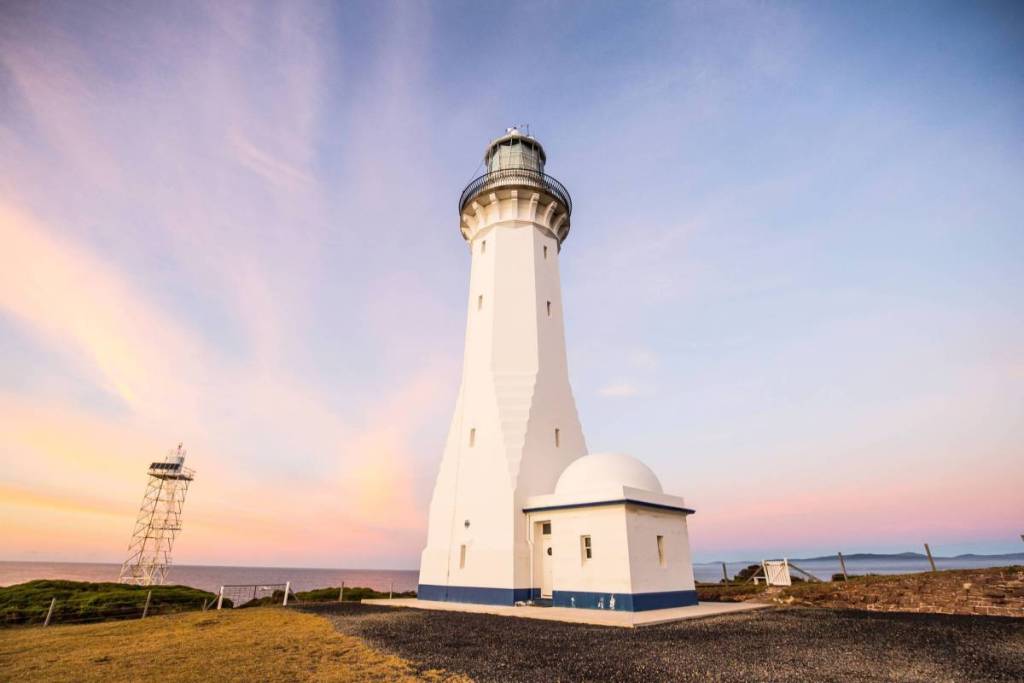 Green Cape Lighthouse on the NSW South Coast, with its white tower standing against a pastel pink and purple sunset sky
