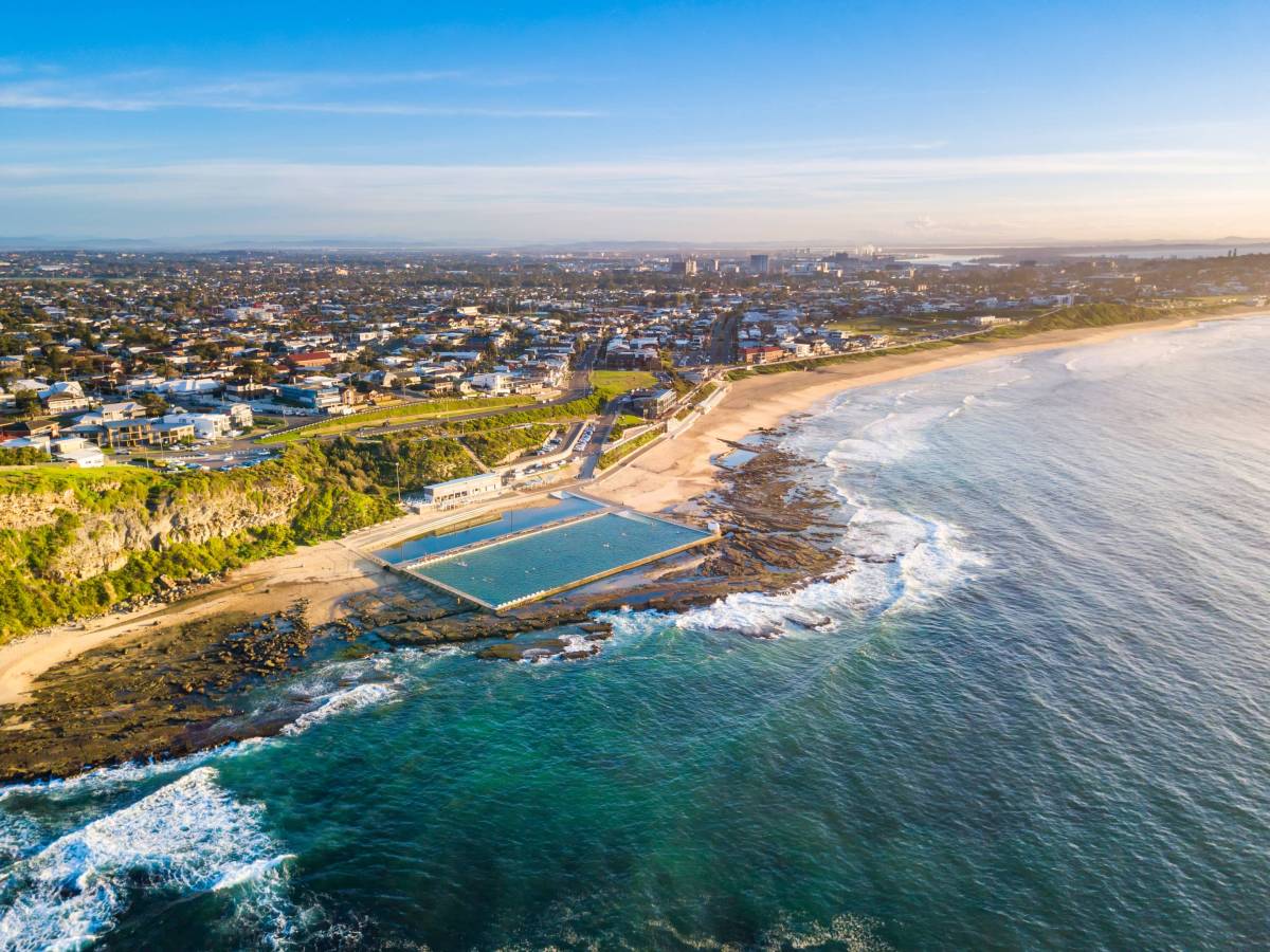 Aerial view of Merewether Ocean Baths nestled along Newcastle's coastline, with sweeping views of the beach, ocean and surrounding suburbs