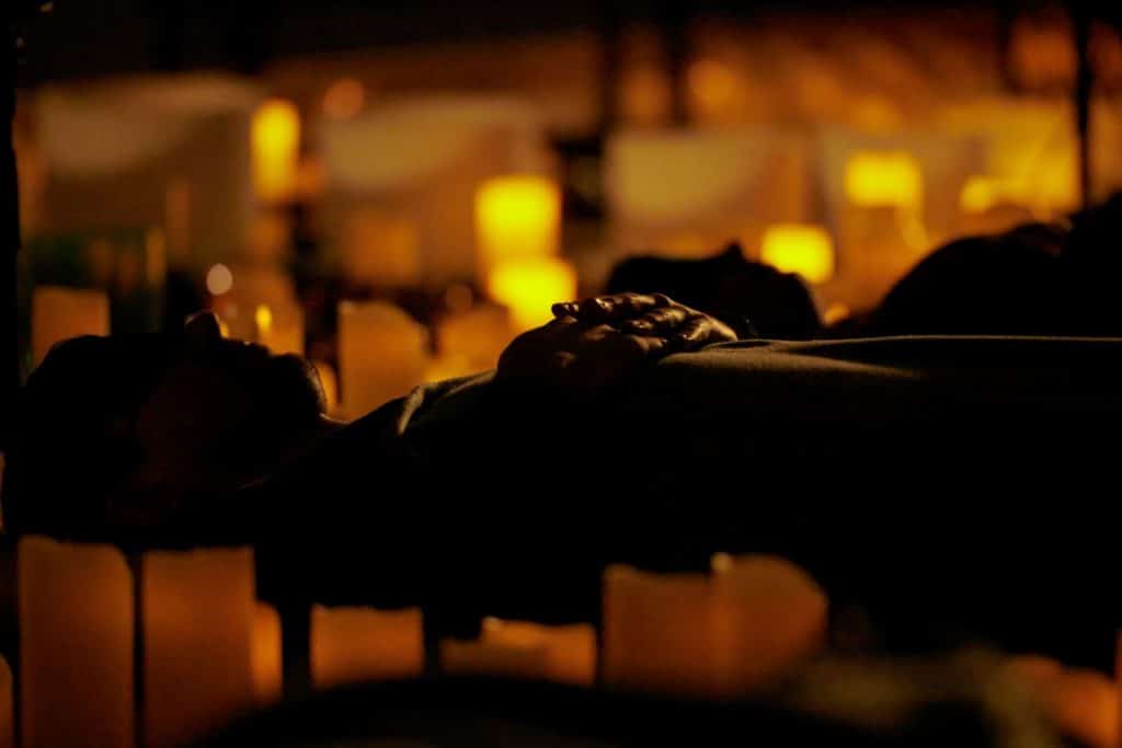 A person lying on the ground surrounded by candles.