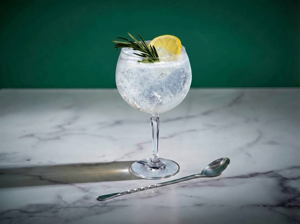 a tanqueray and tonic on a marble worktop with a spring of rosemary and slice of lemon