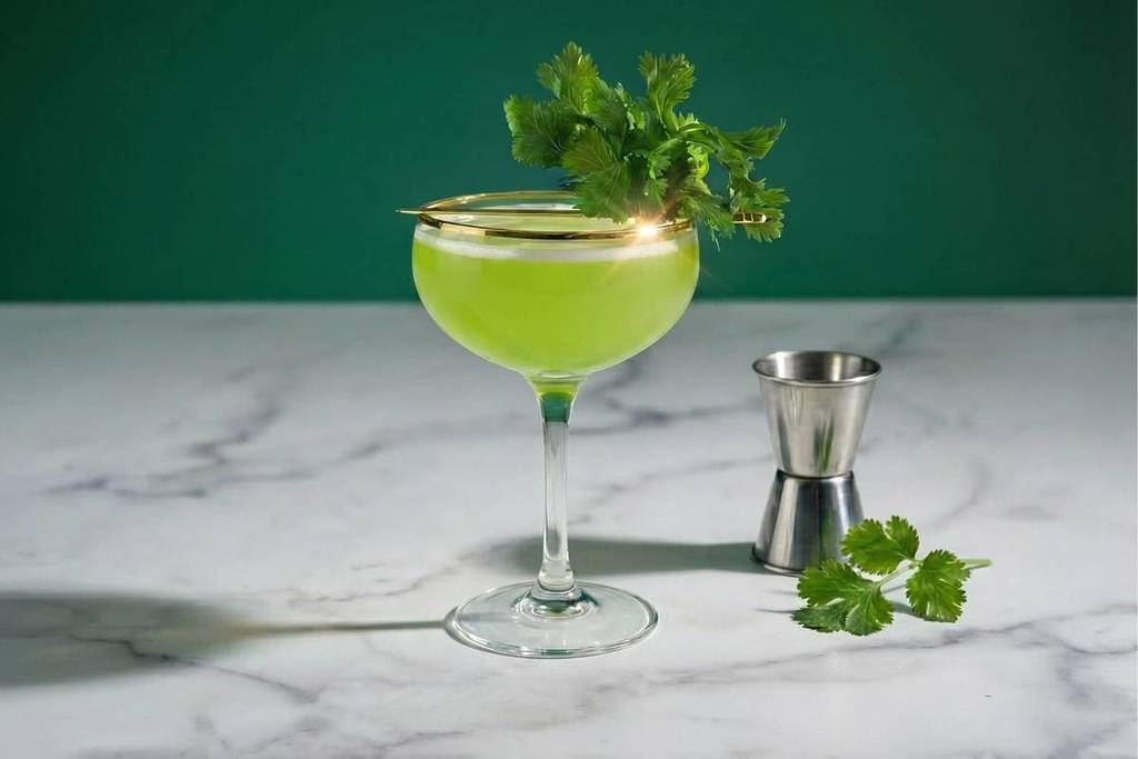 cilantro gimlet cocktail on a marble worktop garnished with cilantro