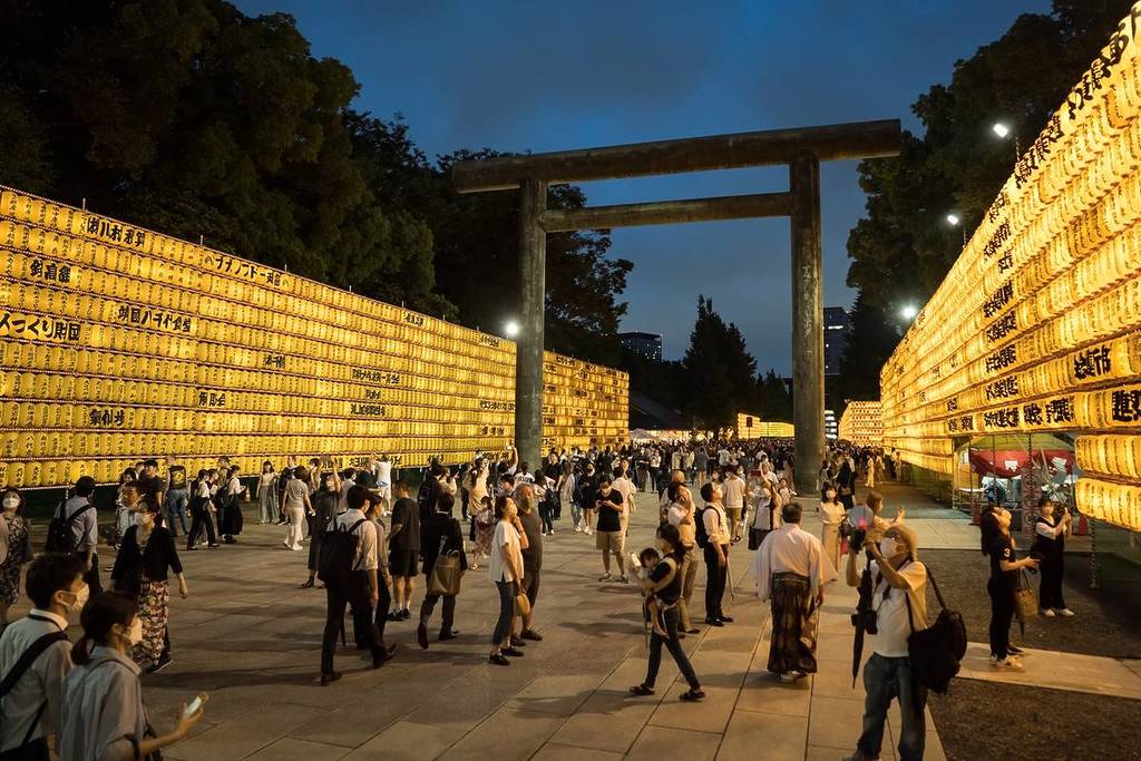 TOKYO, JAPAN - JULY 13: People walk past lit paper lanterns during the Mitama Matsuri summer festival at the Yasukuni Shrine on July 13, 2022 in Tokyo, Japan. About 30,000 lanterns are displayed during the four-day traditional festival taking place during Tokyo's Bon period in July. The controversial Shinto shrine is dedicated to the souls of about 2.5 million Japanese men, women and children who died for their country.