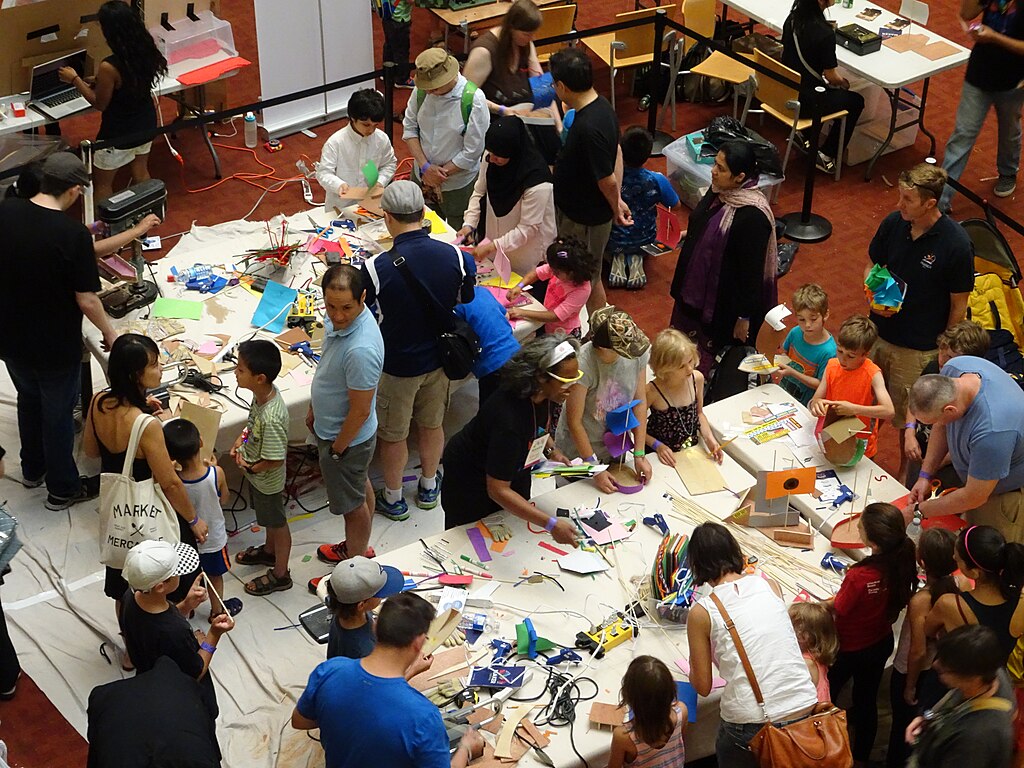 kids play with markers surrounded by adults at a community event in the library