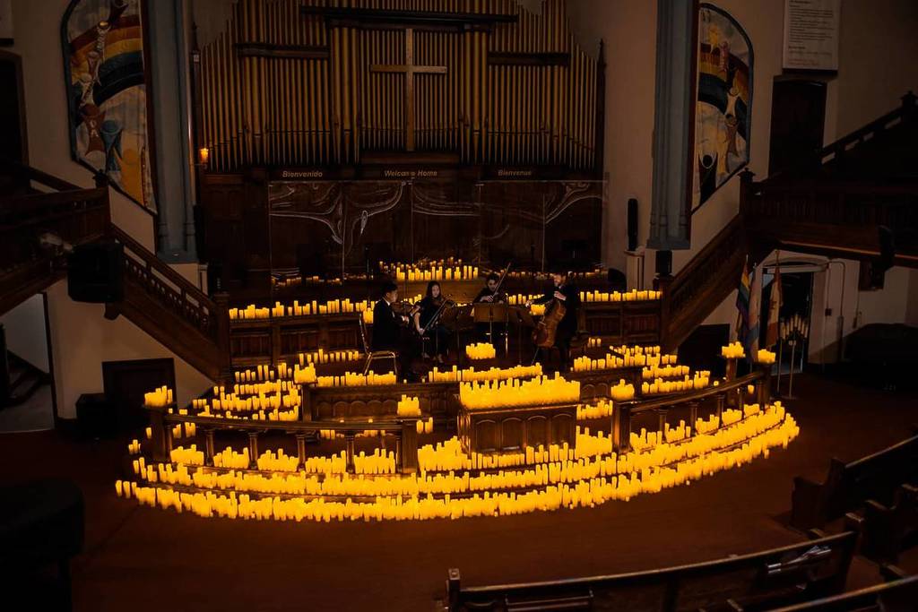 A string quartet performing by candlelight on stage at Metropolitan Community Church of Toronto