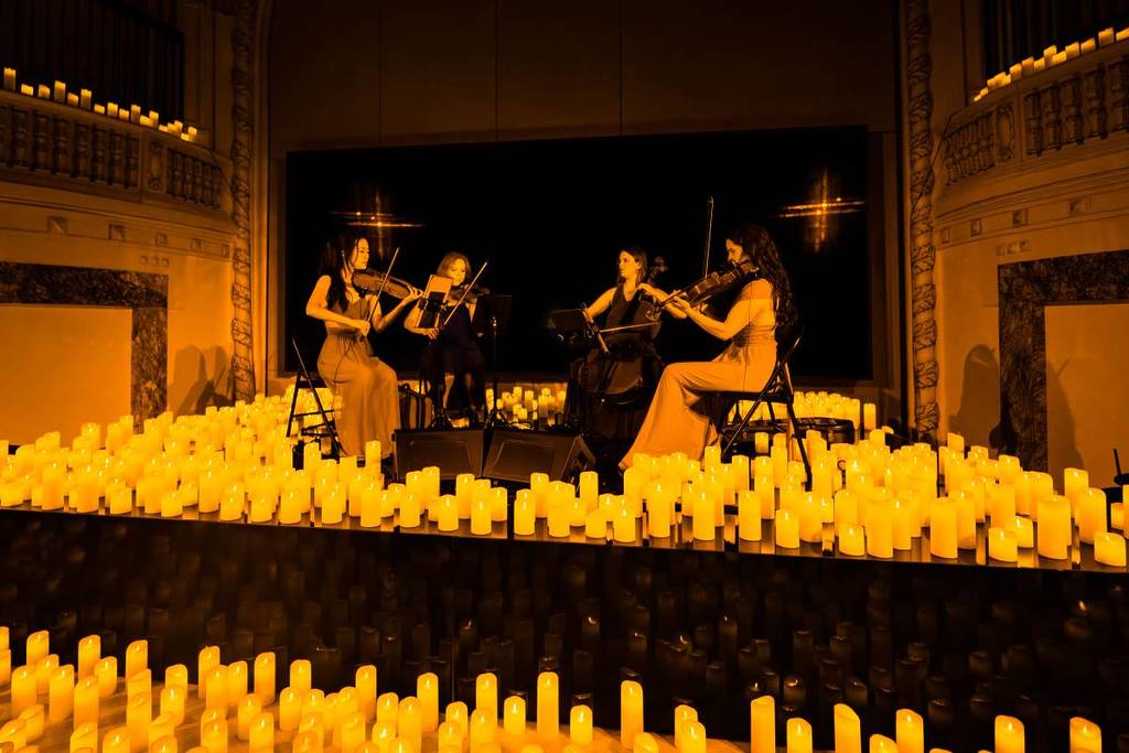 A string quartet performing amid a sea of candles