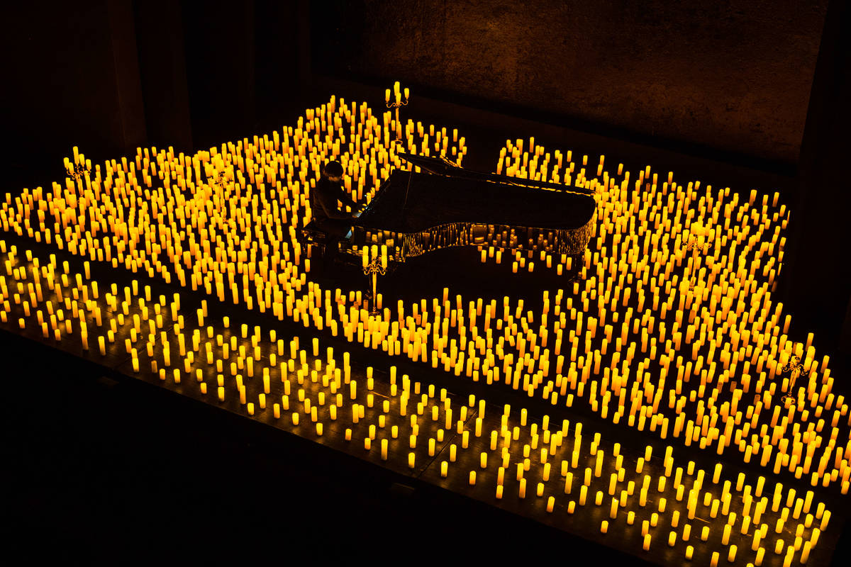 A pianist performs, surrounded by candles at a Candlelight concert.