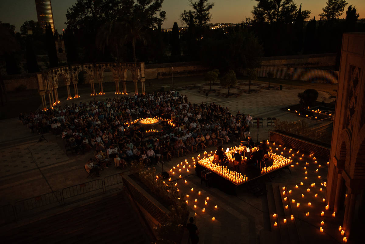 Plano general de un concierto Candlelight en Sevilla donde un cuarteto de cuerda toca sobre un escenario cubierto de cálidas velas.