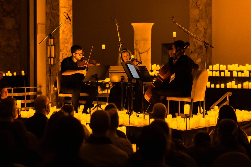 Cuarteto de cuerda tocando en un concierto Candlelight entre miles de velas
