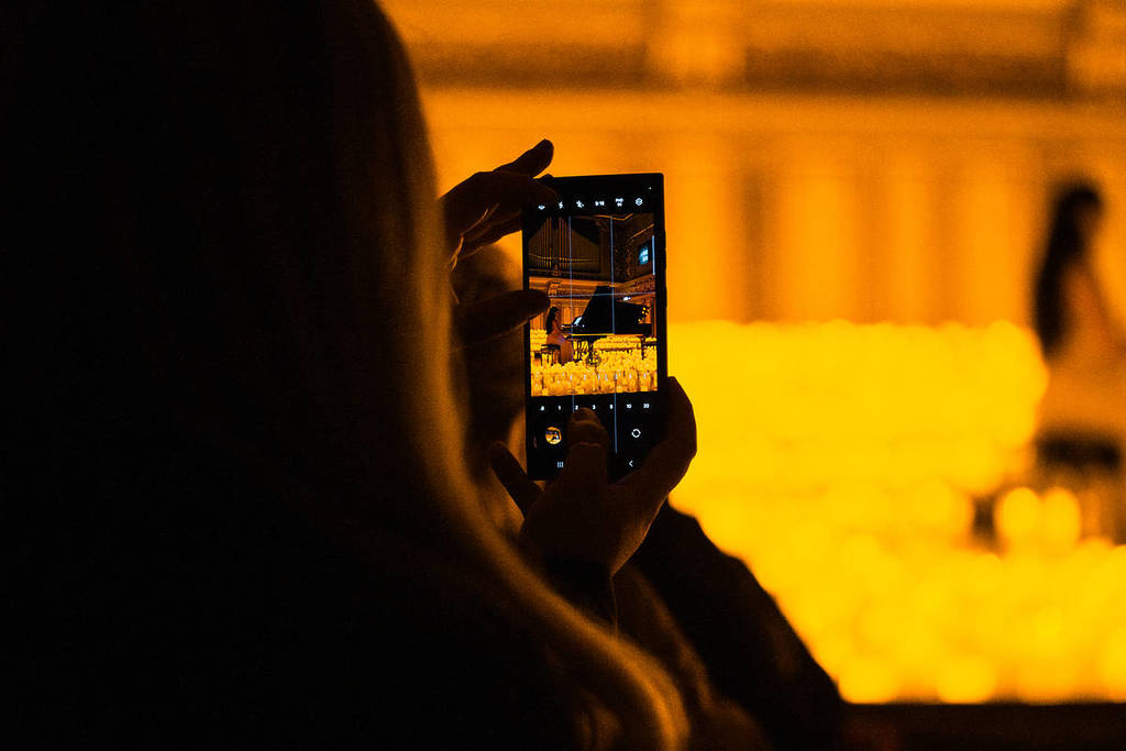 Una chica hace una foto con el móvil durante la última canción de un concierto Candlelight.