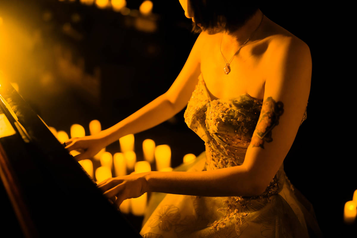 Un pianista suona, circondato da candele.