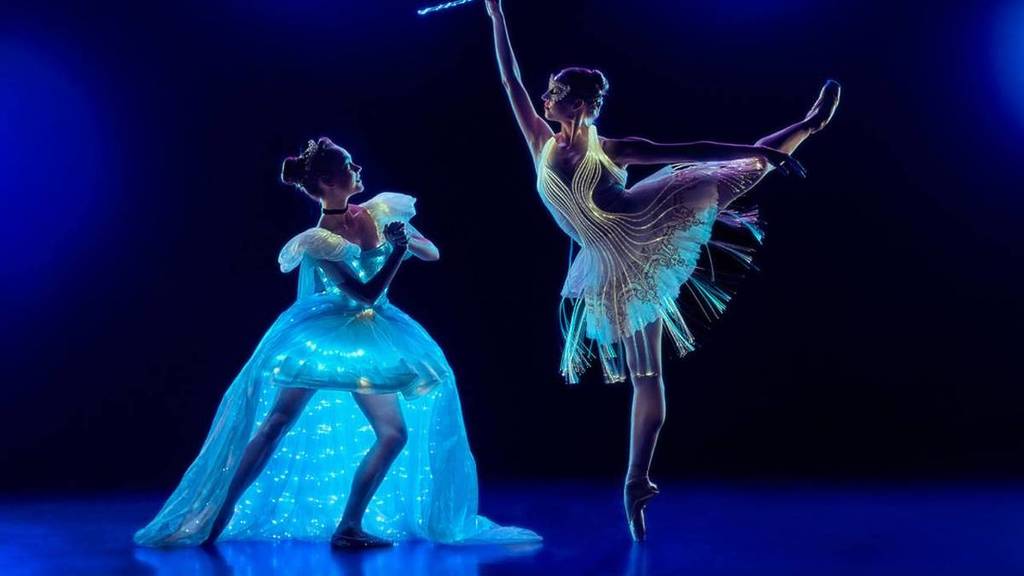Two dancers in luminous costumes in the middle of a performance