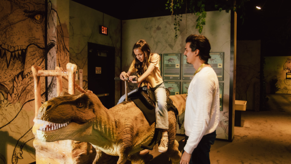 Photo d'une petite fille chevauchant une reproduction de dinosaure