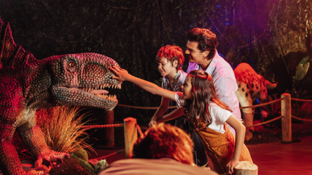 Photo d'enfants s'approchant d'une reproduction de dinosaure taille réélle