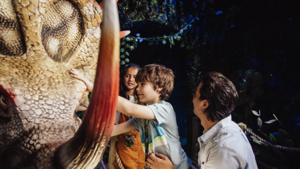 Photo d'enfants s'approchant d'une reproduction de dinosaure taille réélle