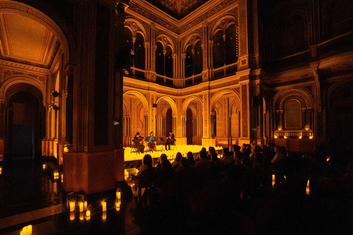Un cuarteto de cuerda toca sobre un escenario cubierto de velas durante un concierto Candlelight en Valencia.