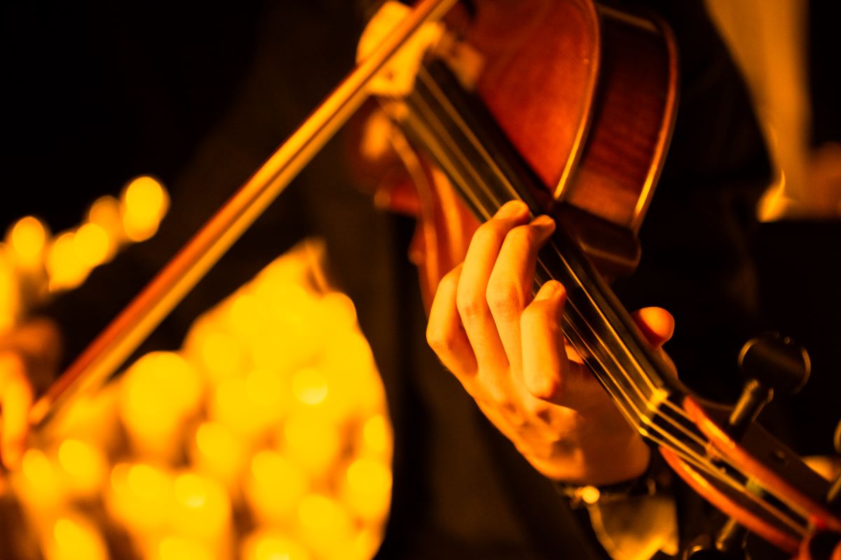 Nahaufnahme von einer Violine, die bei einem Candlelight-Konzert mit etlichen Kerzen im Hintergrund gespielt wird