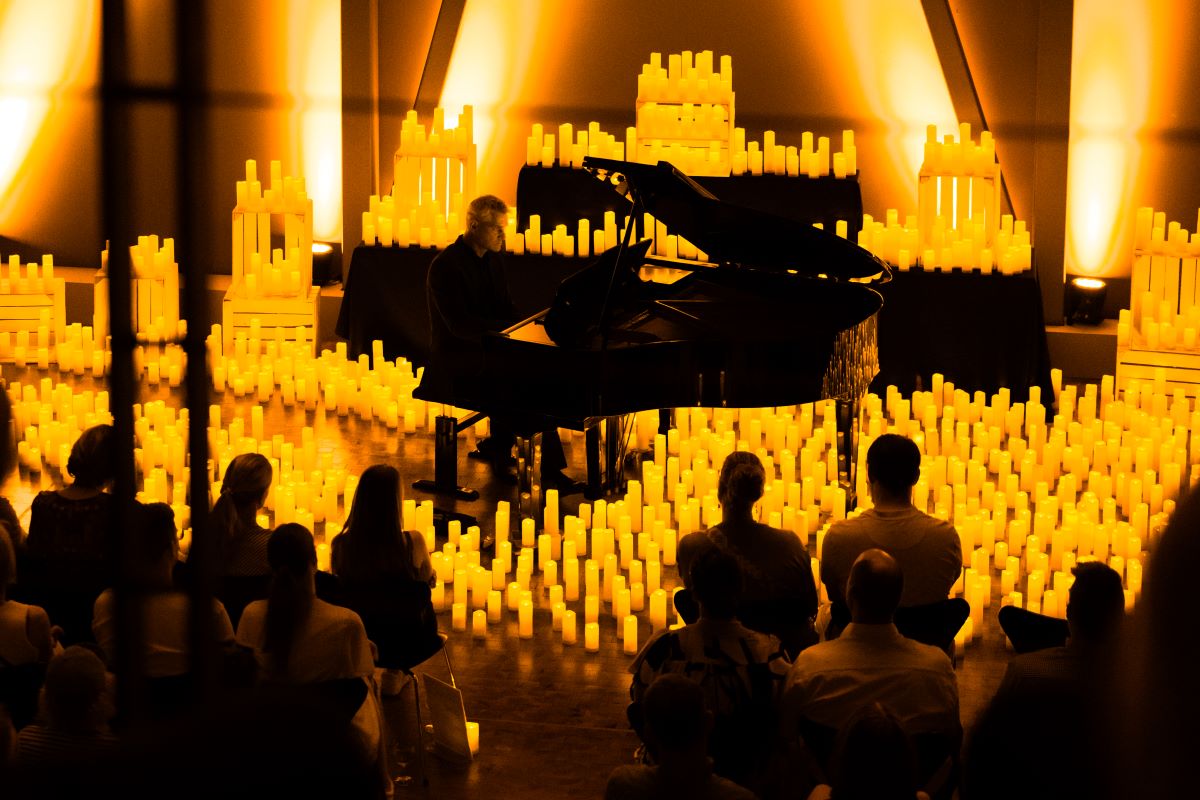Pianist spielt bei einem Candlelight-Konzert auf einem Flügel, umgeben von unzähligen Kerzen