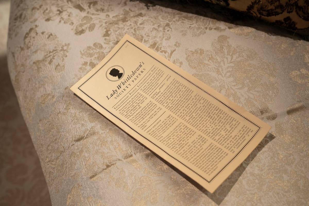 Eine Ausgabe von "Lady Whistledown's Society Papers" aus "Bridgerton" liegt auf einer Decke
