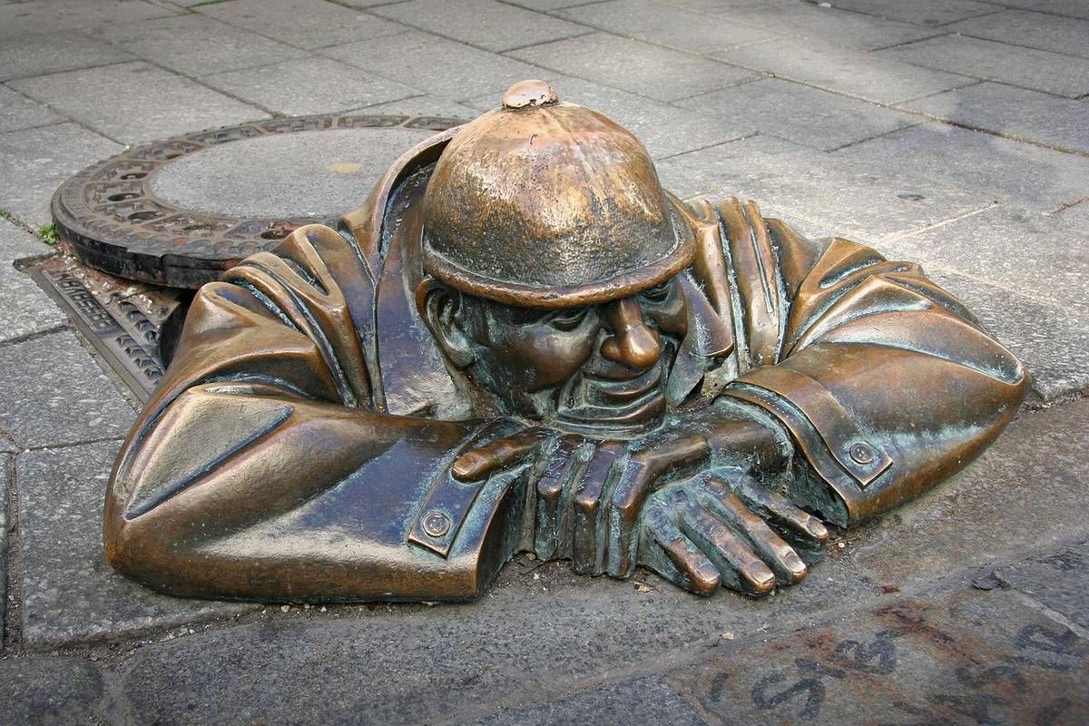 bronzestatute eines mannes, der aus einem gully schaut in brstislava