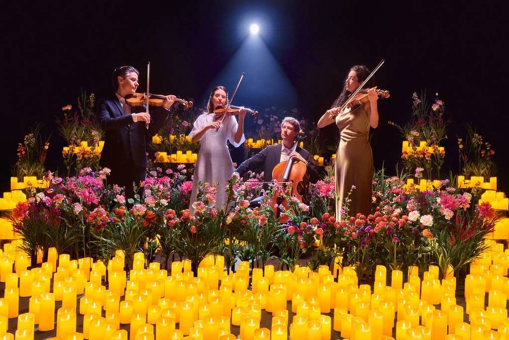 A string quartet plays on the Candlelight Spring stage, surrounded by numerous candles and flowers