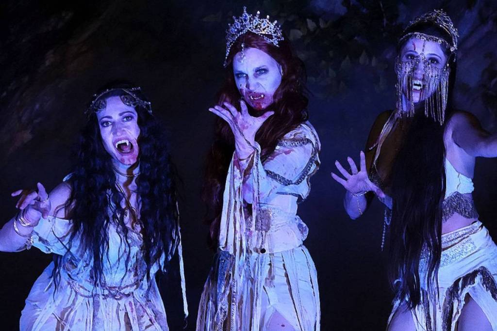 Three blood-stained female vampires in white dresses strike terrifying poses for the spine-chilling Dracula experience at Lockenhaus Castle.