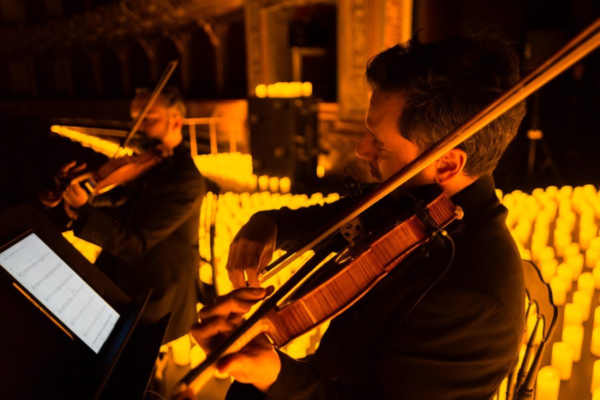 Primer plano de un músico tocando el violín sobre un escenario cubeirto de velas durante un concierto Candlelight en el Teatro Colón de Bogotá.